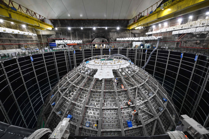 091224_ec_neutrino_inline-4 An experimental hall houses a large spherical apparatus with workers climbing on it.